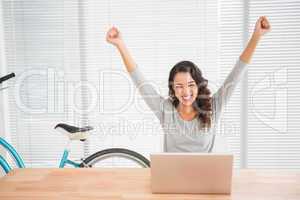 Young businesswoman cheering in front of her laptop