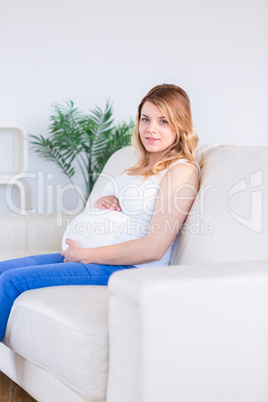 Pregnant woman looking at camera with hands on belly