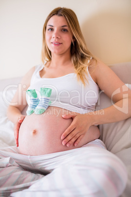 Pregnant woman with baby shoes over bump