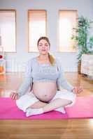Pregnant woman doing yoga on exercise mat
