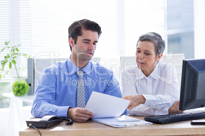 Two business people looking at a paper while working on folder