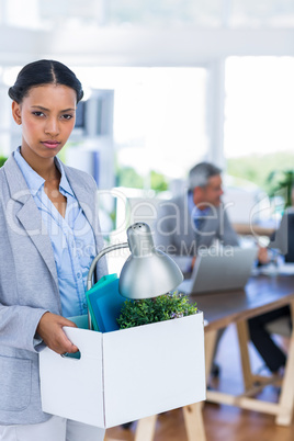 Businesswoman holding box and looking at camera