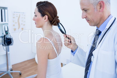 Doctor examining his patient back with magnifying glass