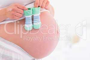 Pregnant woman holding baby shoes over bump