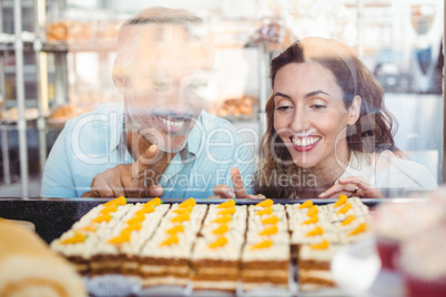 Cute couple pointing pastries through the glass