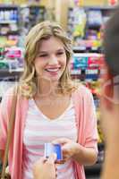 Smiling woman at cash register paying with credit card
