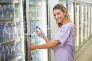 A pretty smiling blonde woman buying water