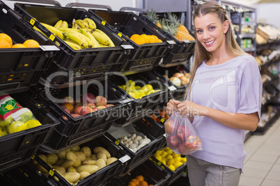 Smiling pretty blonde woman buying apples