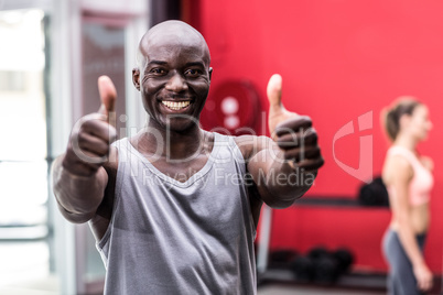Smiling muscular man gesturing thumbs up