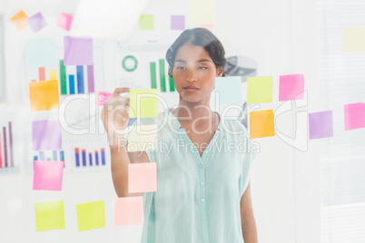 Concentrated businesswoman looking post its on the wall