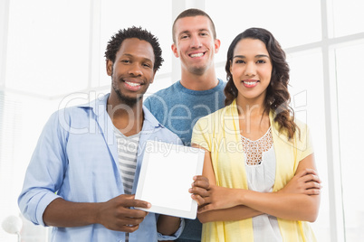 Portrait of smiling colleagues presenting tablet computer and lo