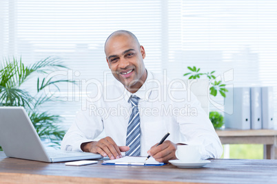 Smiling businessman writing on notebook