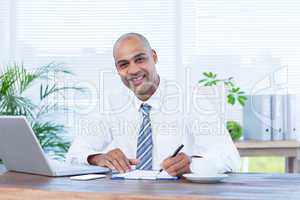 Smiling businessman writing on notebook