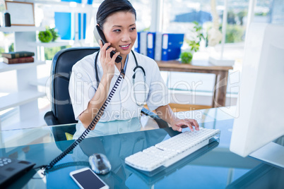 Doctor having phone call and using her computer