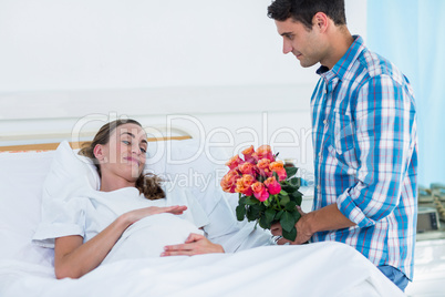 Man offering flowers to pregnant woman in hospital