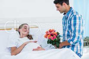 Man offering flowers to pregnant woman in hospital