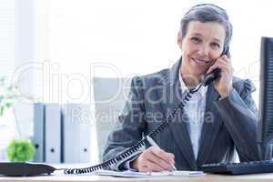 Smiling portrait of a businesswoman phoning and writing