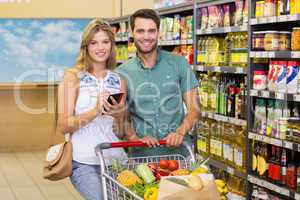 Portrait of smiling bright couple buying food products and using