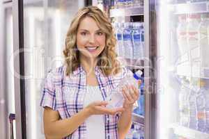 Portrait of a smiling pretty blonde woman taking a water bottle