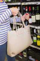 Woman putting a bottle of red wine on her bag