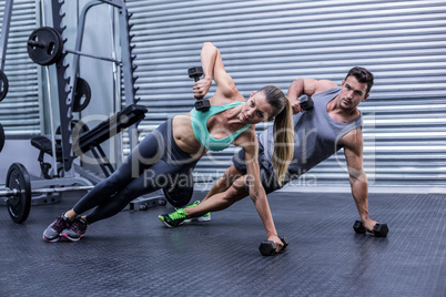 Smiling muscular couple doing side plank