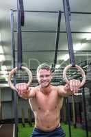 Portrait of smiling muscular man doing ring gymnastics