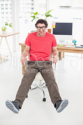 Handsome businessman sitting on a swivel chair and using his la