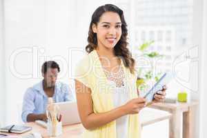 Smiling woman posing in front of her colleague with tablet compu