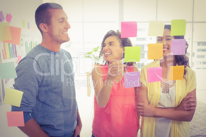 Smiling coworkers pointing sticky notes