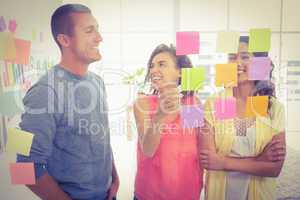 Smiling coworkers pointing sticky notes