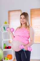 A pregnant woman holding dumbbells