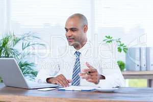 Smiling businessman working on laptop