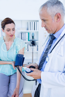 Doctor checking blood pressure of a young woman