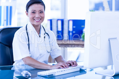 Happy doctor using her computer and looking at camera