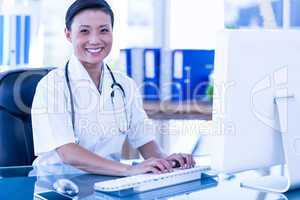 Happy doctor using her computer and looking at camera