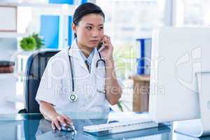 Concentrated doctor having phone call and using her computer