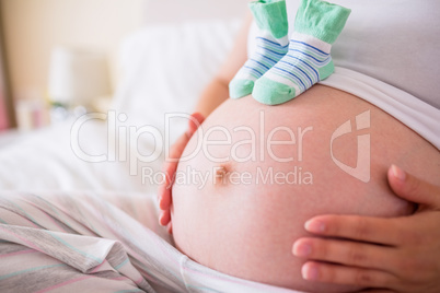 Pregnant woman with baby shoes over bump