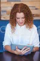 Pretty girl using a small tablet at table