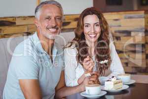 Casual couple having coffee and cake together