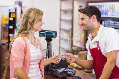 Smiling woman at cash register paying with credit card