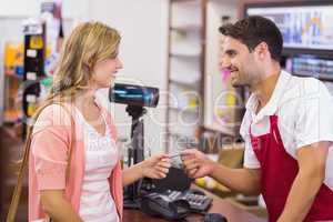 Smiling woman at cash register paying with credit card