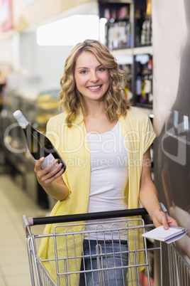 Portrait of a smiling pretty blonde woman having a notepad and w