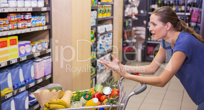 Surprised woman looking at product on shelf