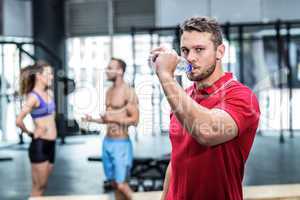 Attentive muscular trainer drinking water