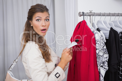 Portrait of surprised woman holding  price tag and looking at ca