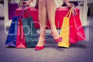 Woman sitting with legs crossed and holding shopping bags