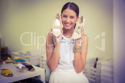 Young happy woman holding a pair of shoes in her hand while look