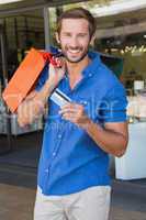 Young happy man holding shopping bags and a credit card