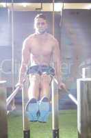 Muscular man exercising on parallel bars