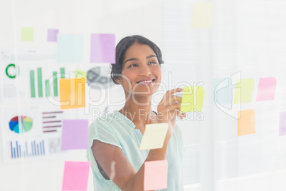 Concentrated businesswoman looking post its on the wall